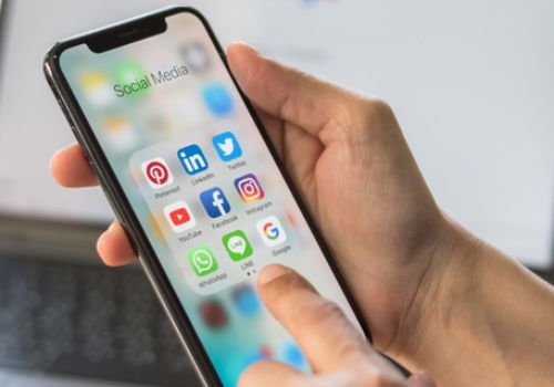 A person using a smartphone displaying a social media app for digital marketing and e-commerce, showcasing multi-channel and cross-channel online technology for managing digital campaigns.